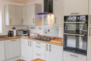 a kitchen with white cabinets and a stove top oven at Fabulous detached lodge with hot tub two nights minimum stay in Bridgnorth