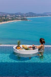 Villa Anushka - Modern luxury villa with picture-perfect sea views في كوه ساموي: امرأة في الماء مع طاولة في مسبح