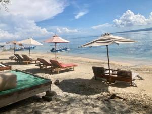 a group of chairs and umbrellas on a beach at Gili Air Santay Bungalows in Gili Air