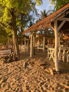 a beach with a hut and chairs on the sand at Gili Air Santay Bungalows in Gili Islands