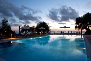 a large swimming pool with a sunset in the background at PANTHEON RESORT AND VILLAS in Agios Nikitas
