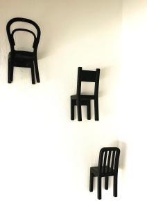 Tre sedie nere sedute su un muro bianco di La Finestra Sull’Oasi a Genova