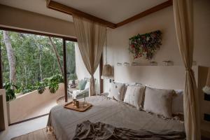 a bedroom with a bed and a large window at Romantic Rubi Tulum in Tulum