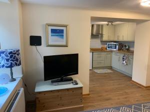 a kitchen with a flat screen tv on a wooden table at Spacious 1 bedroom cottage between coasts in North Hill