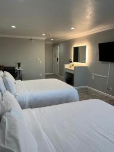 Habitación de hotel con 2 camas y TV de pantalla plana. en Capri Suites Anaheim en Anaheim