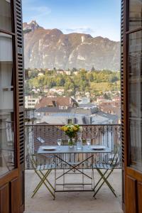 una mesa con un jarrón de flores en el balcón en Villa Saint Enogat, en Aix-les-Bains