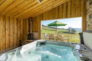 a jacuzzi tub in a cabin with an umbrella at Mill House with Hot Tub in Cray