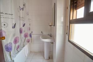 a bathroom with a sink and a shower curtain with purple flowers at Hotel Virgen de los Reyes in Ronda