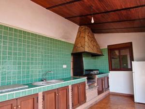 una cucina con pareti piastrellate verdi e stufa di Casa Rural Caminito del Rey ad Alora