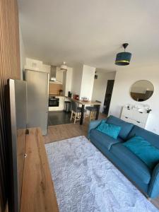 a living room with a blue couch and a kitchen at Superbe T2 proche de la Gare RER TGV Massy Palaiseau in Massy