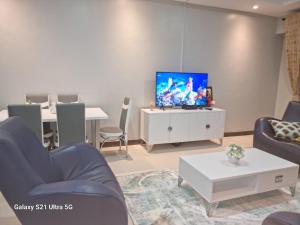 a living room with a tv on a white cabinet at Joy Pristine Nairobi in Silverstone, 2 bed&bathroom, swimming pool, free parking in Nairobi