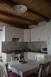 a kitchen with white cabinets and a table with chairs at Casa Claudia - Casa Vacanze in Domegge di Cadore
