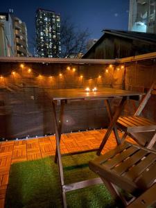 a wooden table and a chair on a patio with lights at 天神橋筋六丁目駅徒歩2分！屋上テラス付き一軒家 天満居酒屋街2分 梅田10分 難波15分 最大13名 in Osaka