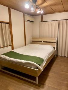 a bedroom with a bed with a green blanket at 天神橋筋六丁目駅徒歩2分！屋上テラス付き一軒家 天満居酒屋街2分 梅田10分 難波15分 最大13名 in Osaka