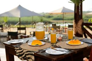 a table with plates of food and orange juice at Selous Kulinda Camp in Selous Game Reserve
