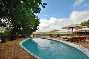 una piscina con tavoli, ombrelloni e tavoli di Selous Kulinda Camp a Selous Game Reserve