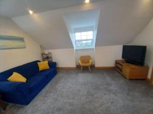 uma sala de estar com um sofá azul e uma televisão em The Apartment em Langley Park