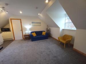 a living room with a blue couch and a chair at The Apartment in Langley Park