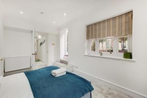 um quarto branco com uma cama azul e janelas em The Belgravia Residences em Londres
