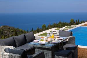 a patio with a table and chairs next to a pool at PANTHEON RESORT AND VILLAS in Agios Nikitas