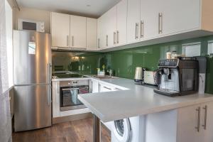 a kitchen with stainless steel appliances and green walls at Andrea Apartment in Liepāja