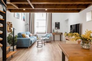 een woonkamer met een blauwe bank en een tafel bij Capricho de Quevedo in Sevilla