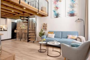 een woonkamer met een blauwe bank en een keuken bij Capricho de Quevedo in Sevilla