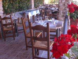 un ristorante con tavoli e sedie con fiori rossi di La Locanda Del Colle a Canalicchio