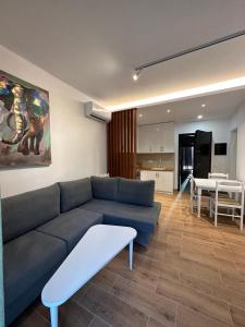 a living room with a blue couch and a kitchen at Bonaparte apartments in Vlorë