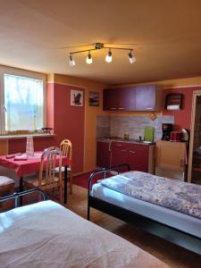 a room with two beds and a table and a kitchen at Südländische Flair in Neubiberg