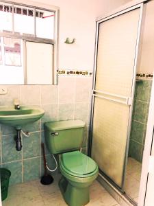 baño con aseo verde y lavamanos en Acogedora casa condominio con piscina en Girardot, en Girardot