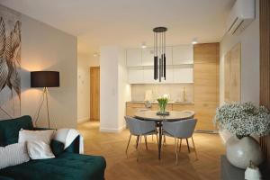 a living room with a green couch and a table at Sand & Wave - Luxury Marina View Apartment with Spa, Pool & Free Parking in Dziwnów