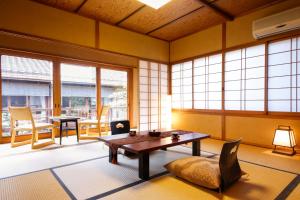 a living room with a table and chairs and windows at Ryokan Sanga in Kyoto