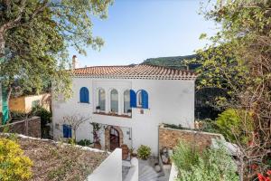 una casa bianca con finestre blu e alberi di Flateli Sa Tuna 3 a Begur