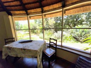 a table and two chairs in a room with a large window at Kiaat Bungalows in Hazyview