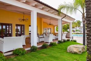Marina Torre Navarrese Resort في سانتا ماريا نافاريز: فناء به كراسي بيضاء ومسبح