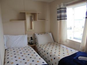 two beds in a small room with a window at 6 Berth on Golden Anchor (Cascade) in Chapel Saint Leonards