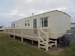 a white tiny house with a porch and a deck at 6 Berth on Golden Anchor (Cascade) in Chapel Saint Leonards