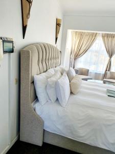 a bedroom with a large white bed with a large window at La Grace Executive Guesthouse in Amsterdamhoek