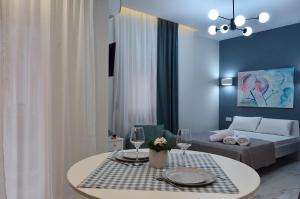 een woonkamer met een bank en een tafel met wijnglazen bij Ippokratio Luxury Studio in Thessaloniki
