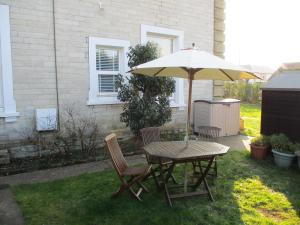 a table and chairs under an umbrella in a yard at Lovely Spacious 3 Bedded First Floor Apartment in Ryde