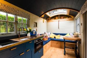 a kitchen with blue cabinets and a blue couch at Nutkins Luxury Shepherd Hut with hot tub close to Lyme Regis in Uplyme