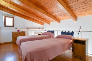 two beds in a room with wooden ceilings at Moon Smile in Massa Lubrense