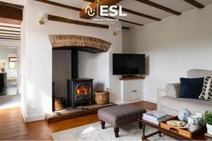 ein Wohnzimmer mit Kamin und Couch in der Unterkunft Luxurious 2 Bedroom Countryside Hot Tub Retreat in Stiperstones in Shelve