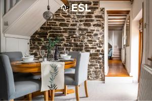 ein Esszimmer mit einer Steinmauer sowie einem Tisch und Stühlen in der Unterkunft Luxurious 2 Bedroom Countryside Hot Tub Retreat in Stiperstones in Shelve