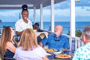 Eine Gruppe von Menschen, die an einem Tisch sitzen und Essen essen. in der Unterkunft Harbour View Boutique Hotel & Yoga Retreat in Belize City