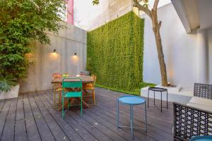 a patio with a table and chairs and a green wall at The Lx Hill in Lisbon