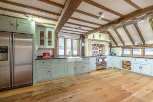 uma grande cozinha com armários brancos e electrodomésticos de aço inoxidável em Family Friendly Retreat Dorney,Windsor em Buckinghamshire
