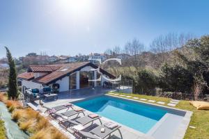 una piscina con tumbonas y una casa en PROMO Easy Clés - 5 bedrooms villa heated pool AC, en San Juan de Luz