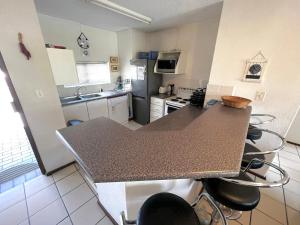 a kitchen with a counter top and chairs in it at Laguna La Crete 216, Beach Front Holiday Apartment in Margate